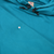 Close-up of teal blue hoodie front showing a small marked spot below the black hood toggles