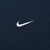 Close-up of small white Nike Swoosh embroidery on navy blue fabric