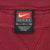Close-up of Nike Team L/G neck tag inside burgundy crewneck sweatshirt