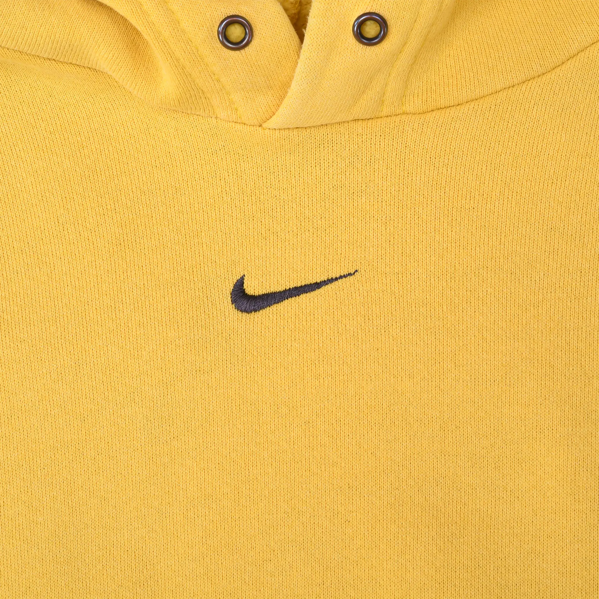 Close-up of small black Nike Swoosh embroidery centered below the hood opening