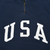 Close-up of white USA chest print and quarter zipper on navy sweatshirt