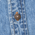 Close-up of Levi Strauss branded metal button and orange stitching on blue denim shirt