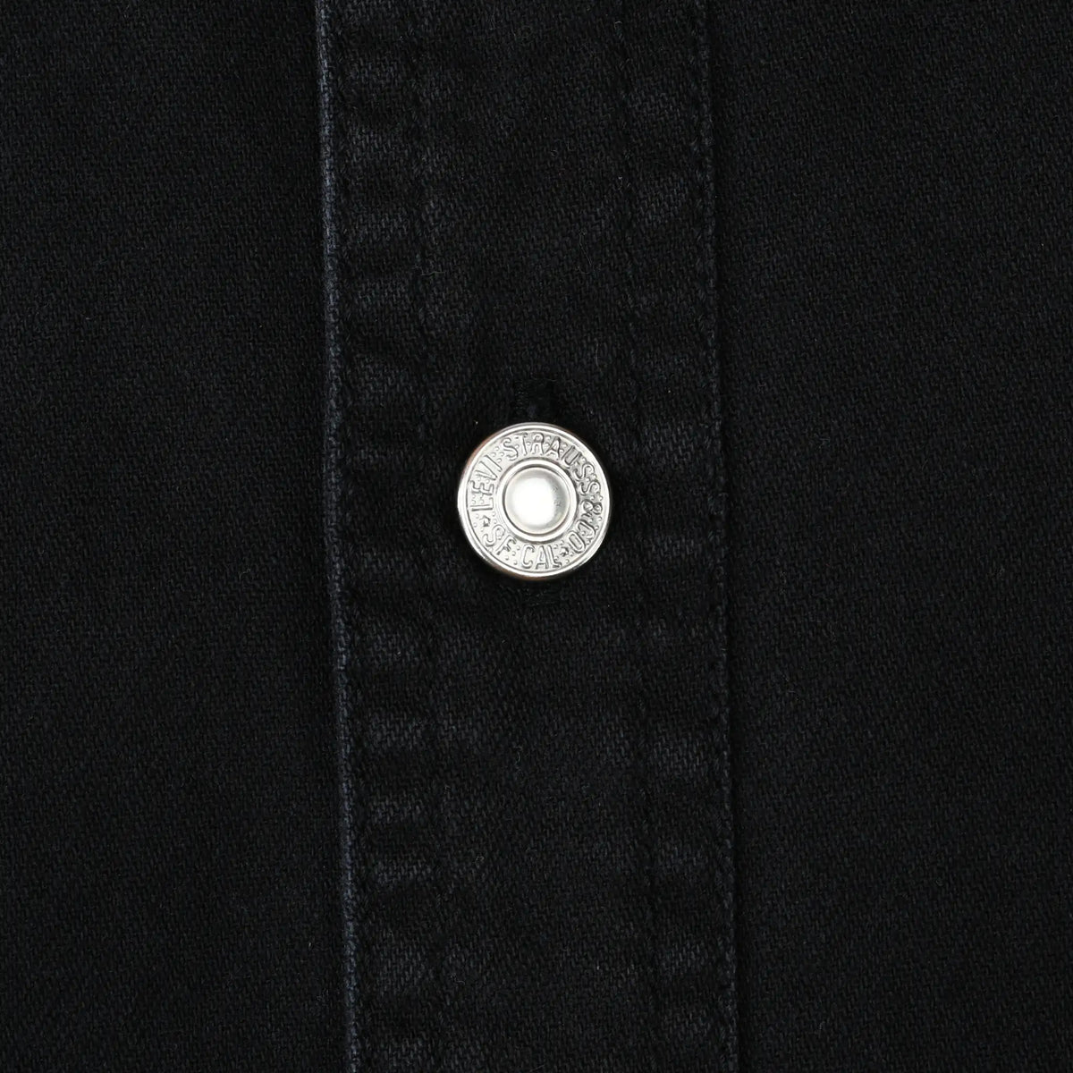 Close-up of silver Levi Strauss branded snap on black denim shirt placket