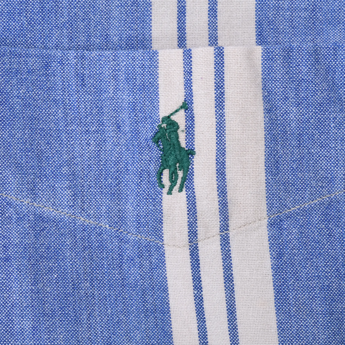 Green Polo pony embroidery on chest pocket of blue and white striped shirt