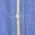 Close-up of white front button and yellow stripe on blue shirt fabric