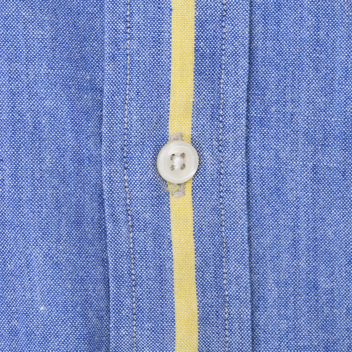 Close-up of white front button and yellow stripe on blue shirt fabric