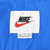 Nike neck label with black logo, red Swoosh, and large size marking on blue fabric