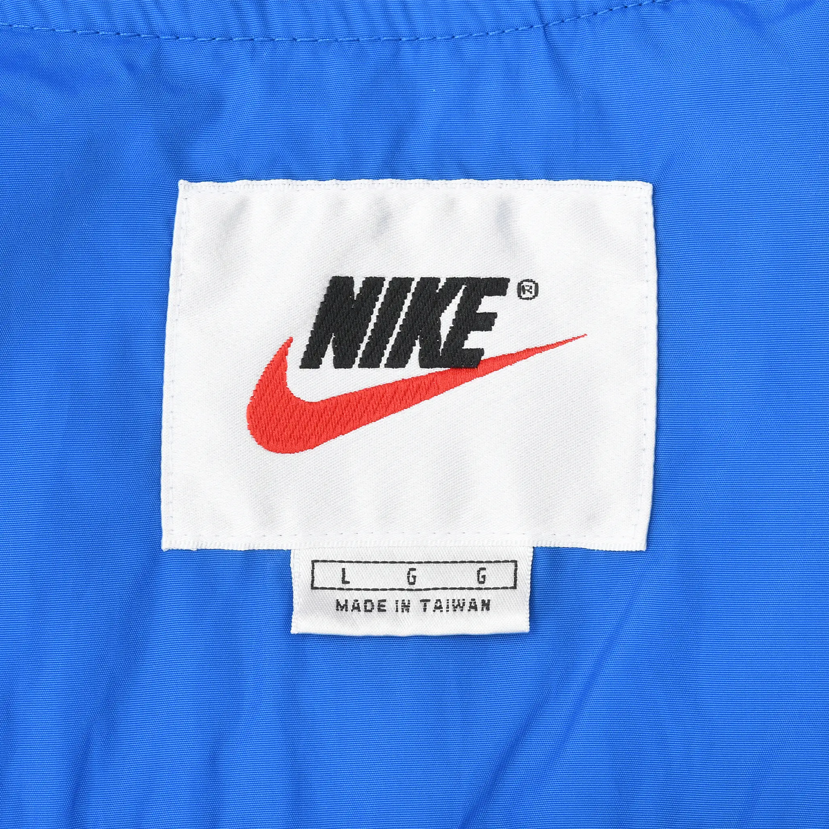 Nike neck label with black logo, red Swoosh, and large size marking on blue fabric