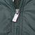 Close-up of silver zipper pull and stitching on green Nike windbreaker