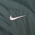 Close-up of white Nike Swoosh embroidery on green fabric