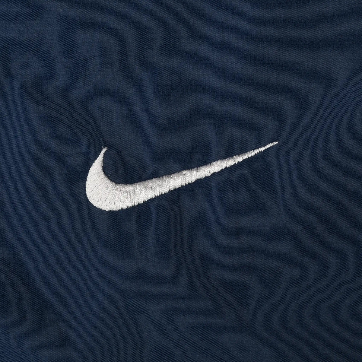 Close-up of white Nike Swoosh embroidery on navy fabric