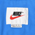 Close-up of white Nike neck label with black logo and red Swoosh on blue fabric