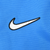 Close-up of white Nike Swoosh embroidery outlined in black on blue fabric