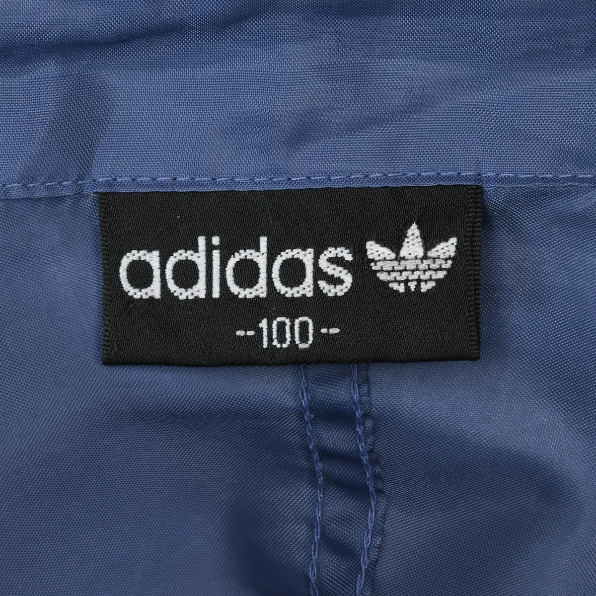 Black Adidas neck label with white wordmark and Trefoil logo on blue lining