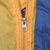 Close-up of silver zipper pull on yellow and blue windbreaker panels