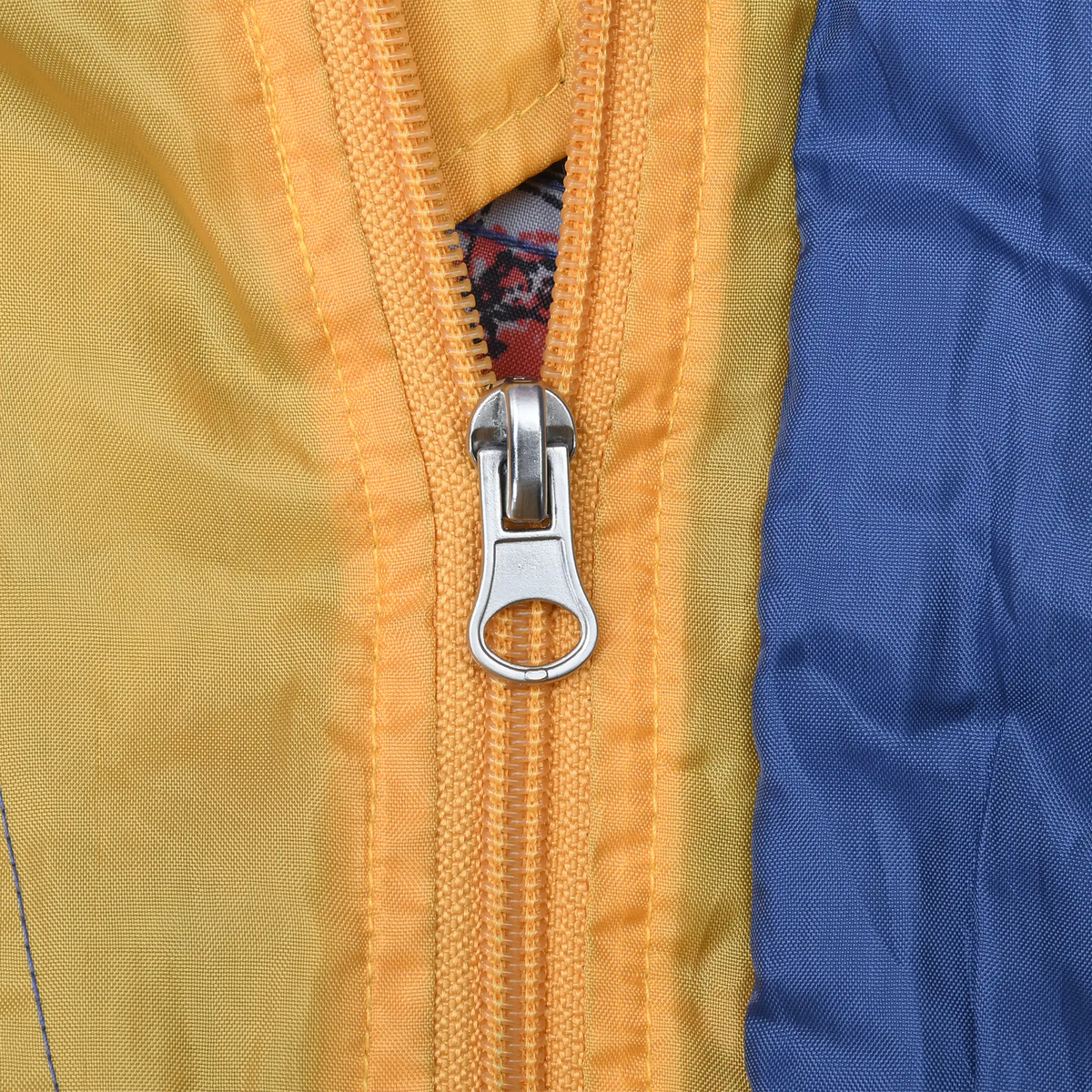 Close-up of silver zipper pull on yellow and blue windbreaker panels