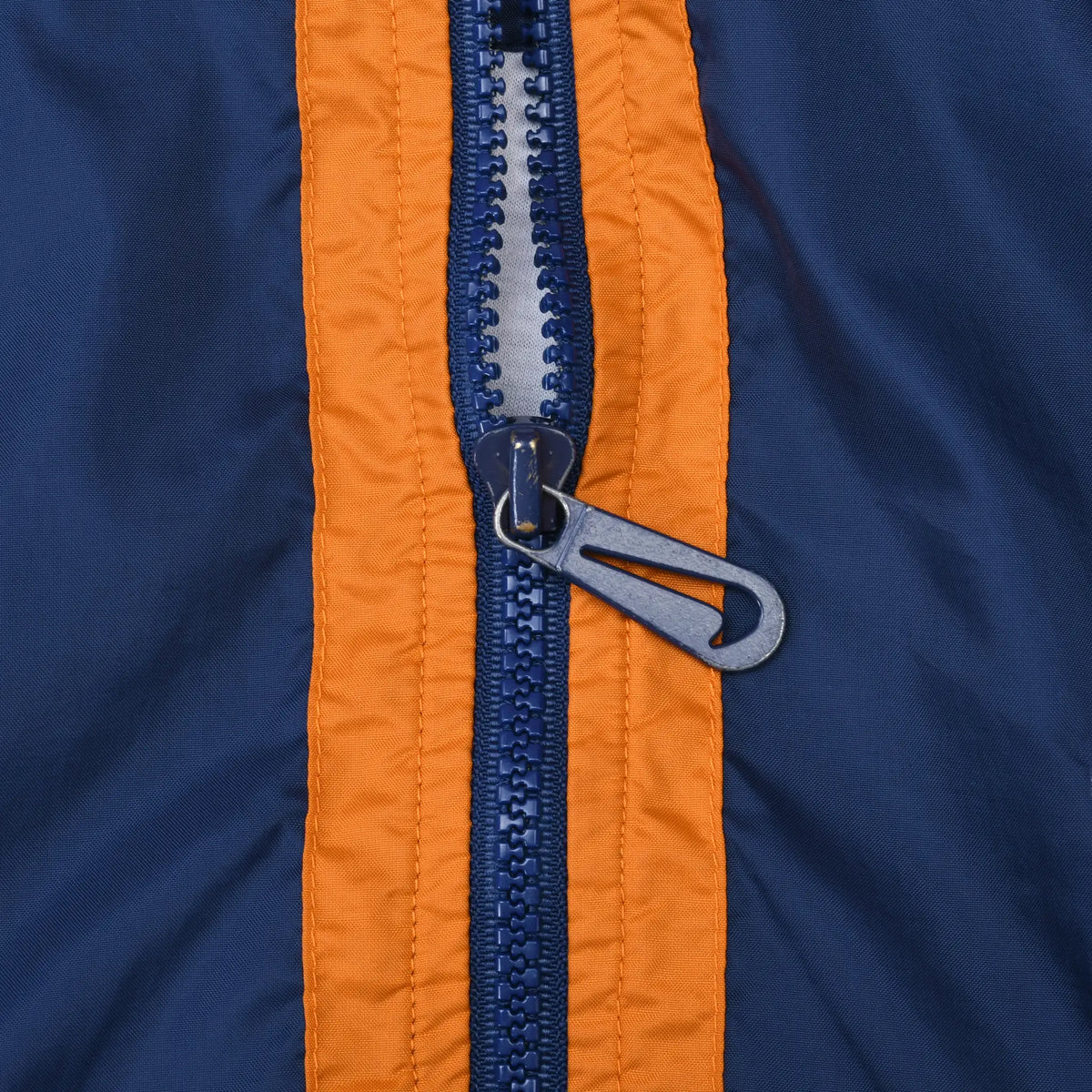 Close-up of navy zipper and Nike Swoosh pull between orange trim
