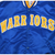 Close-up of gold and white Warriors lettering and snap closures on blue jacket front