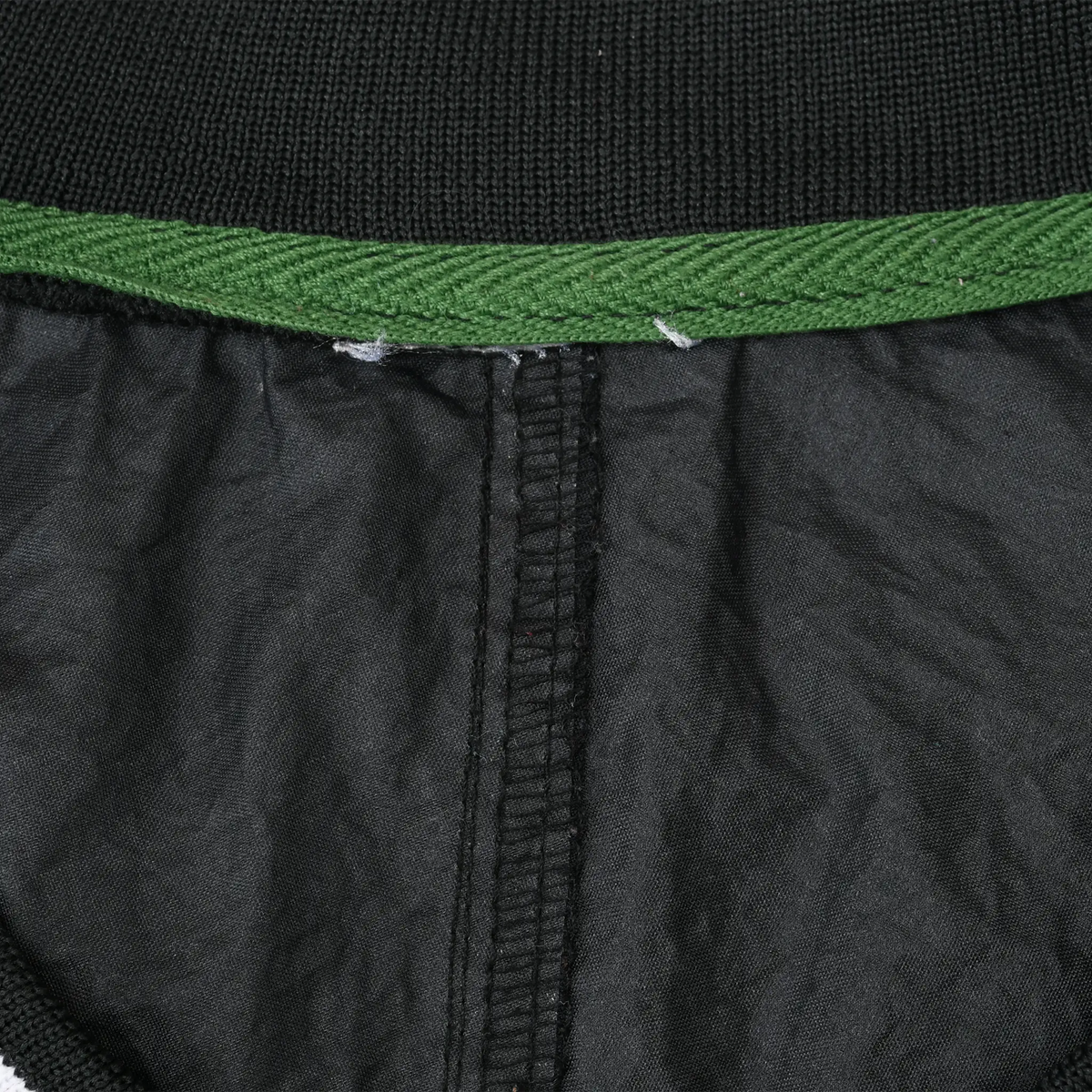 Interior collar detail of black Nike windbreaker with green trim and center seam
