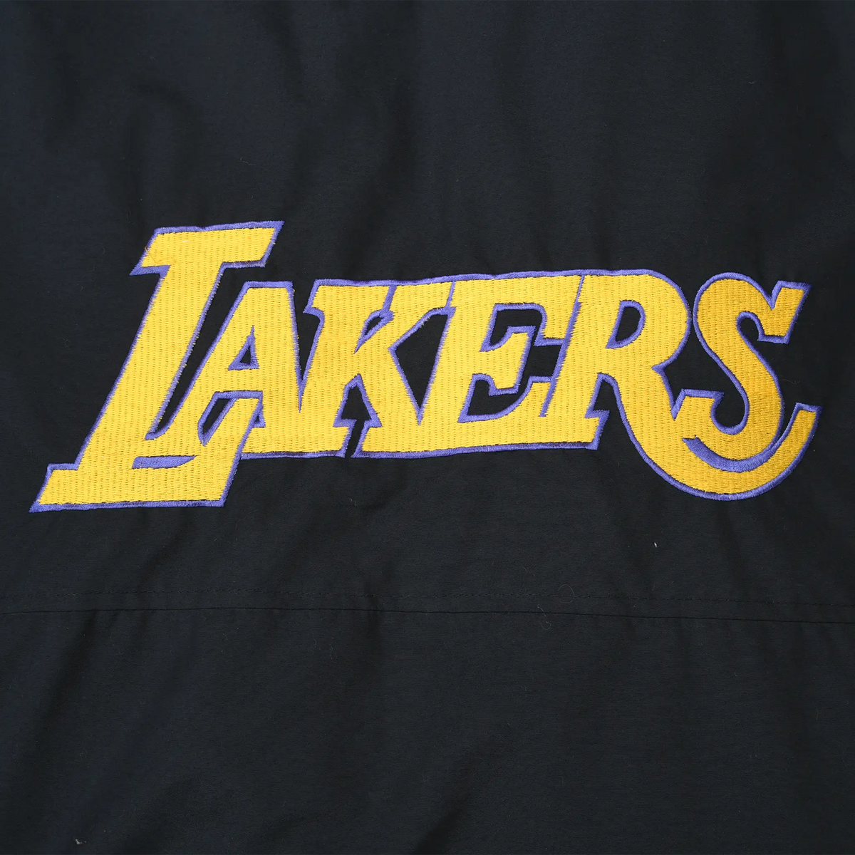 Close-up of large gold Lakers logo with purple outline on back of black jacket