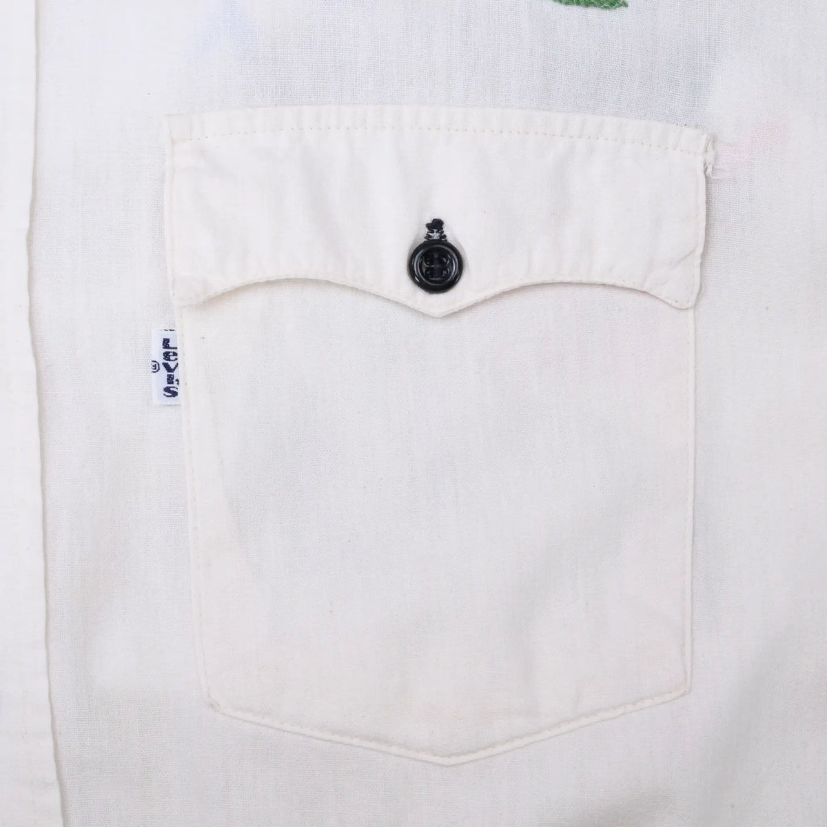 Close-up of white chest pocket with black button and small Levi's side tab