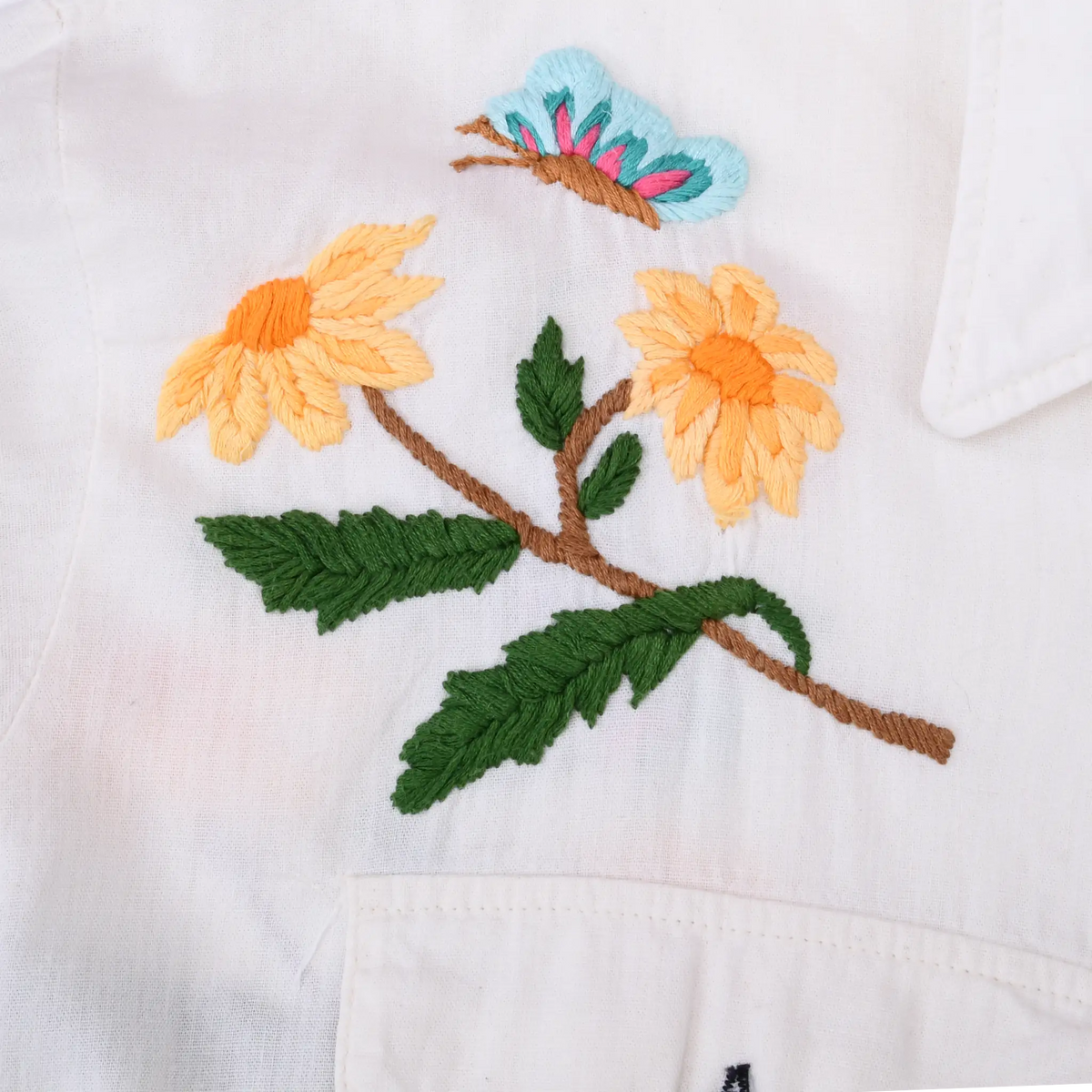 Close-up of orange flower, green leaf, and blue butterfly embroidery on white fabric