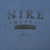Close-up of black Nike Athletics and swoosh chest print on blue-grey fabric