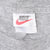 Close-up of Nike neck tag with black logo, red Swoosh, and L size mark