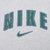 Close-up of green Nike spellout and Swoosh print outlined in navy on grey fabric
