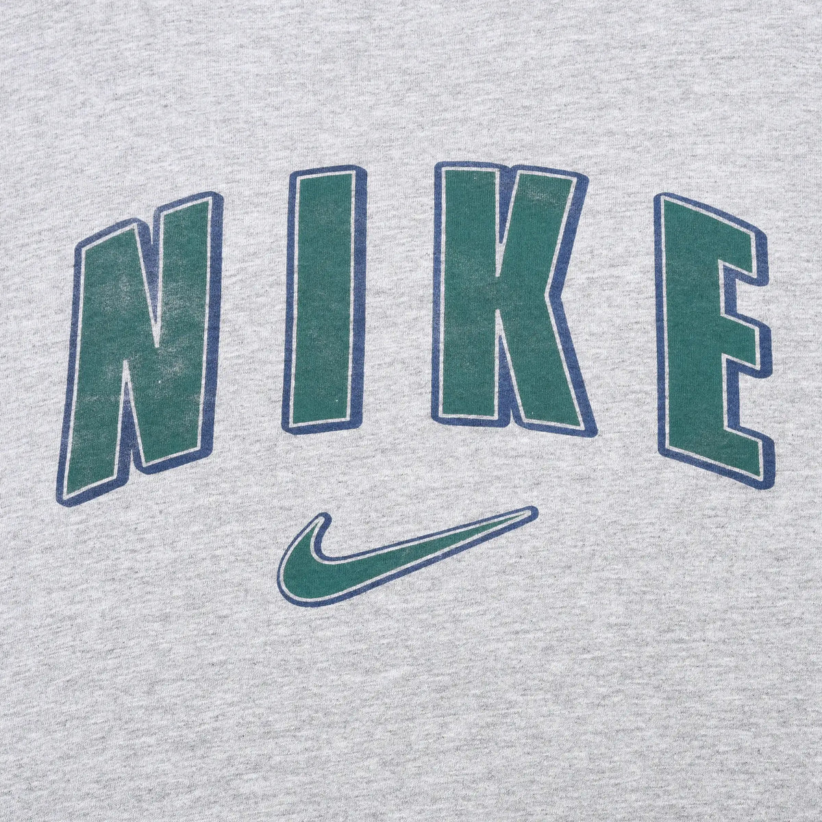 Close-up of green Nike spellout and Swoosh print outlined in navy on grey fabric