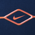 Close-up of orange Nike Swoosh and diamond print on navy blue fabric
