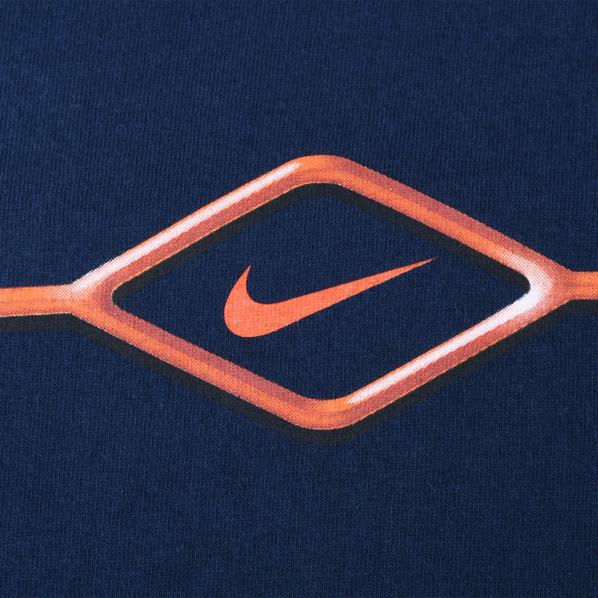 Close-up of orange Nike Swoosh and diamond print on navy blue fabric