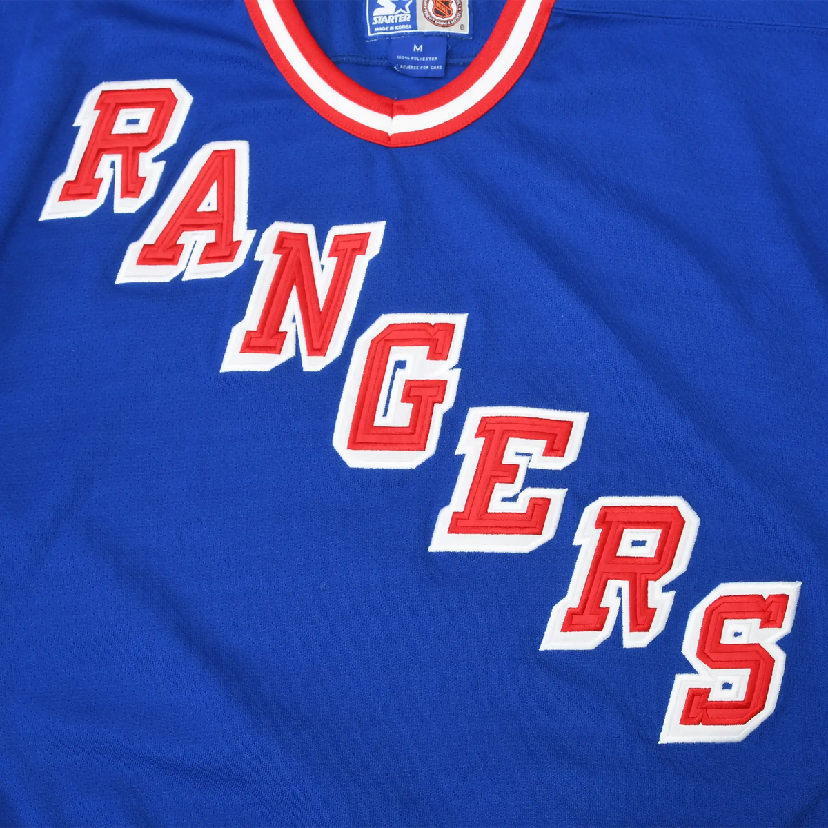 Close-up of diagonal red and white Rangers lettering on blue jersey front