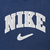 Close-up of gray Nike spellout and Swoosh embroidery on navy blue fabric