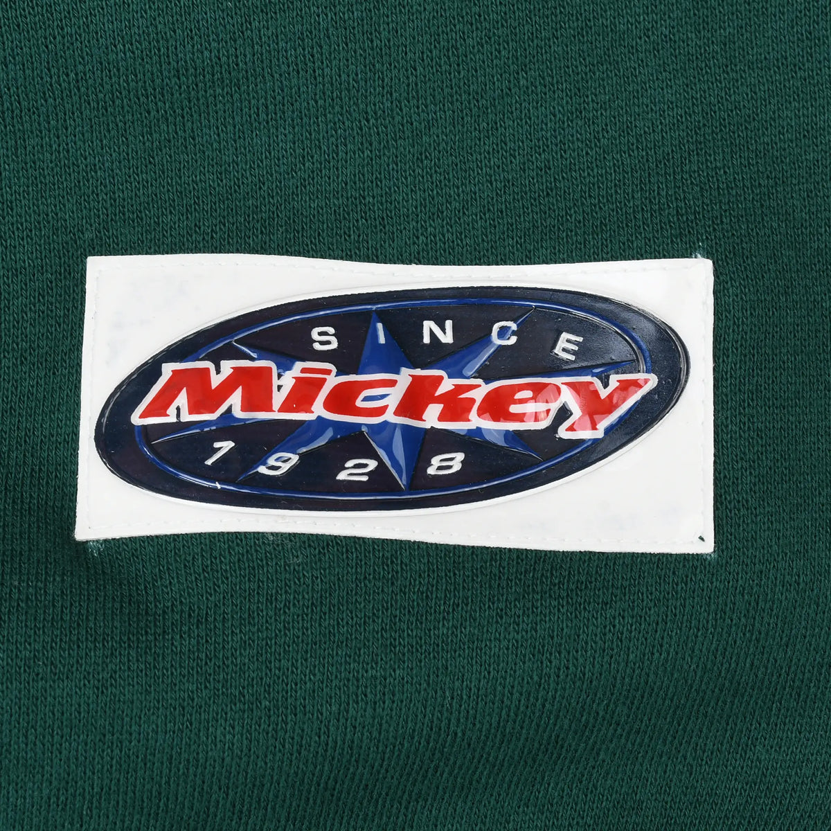 Close-up of oval Mickey Since 1928 patch near the sweatshirt hem