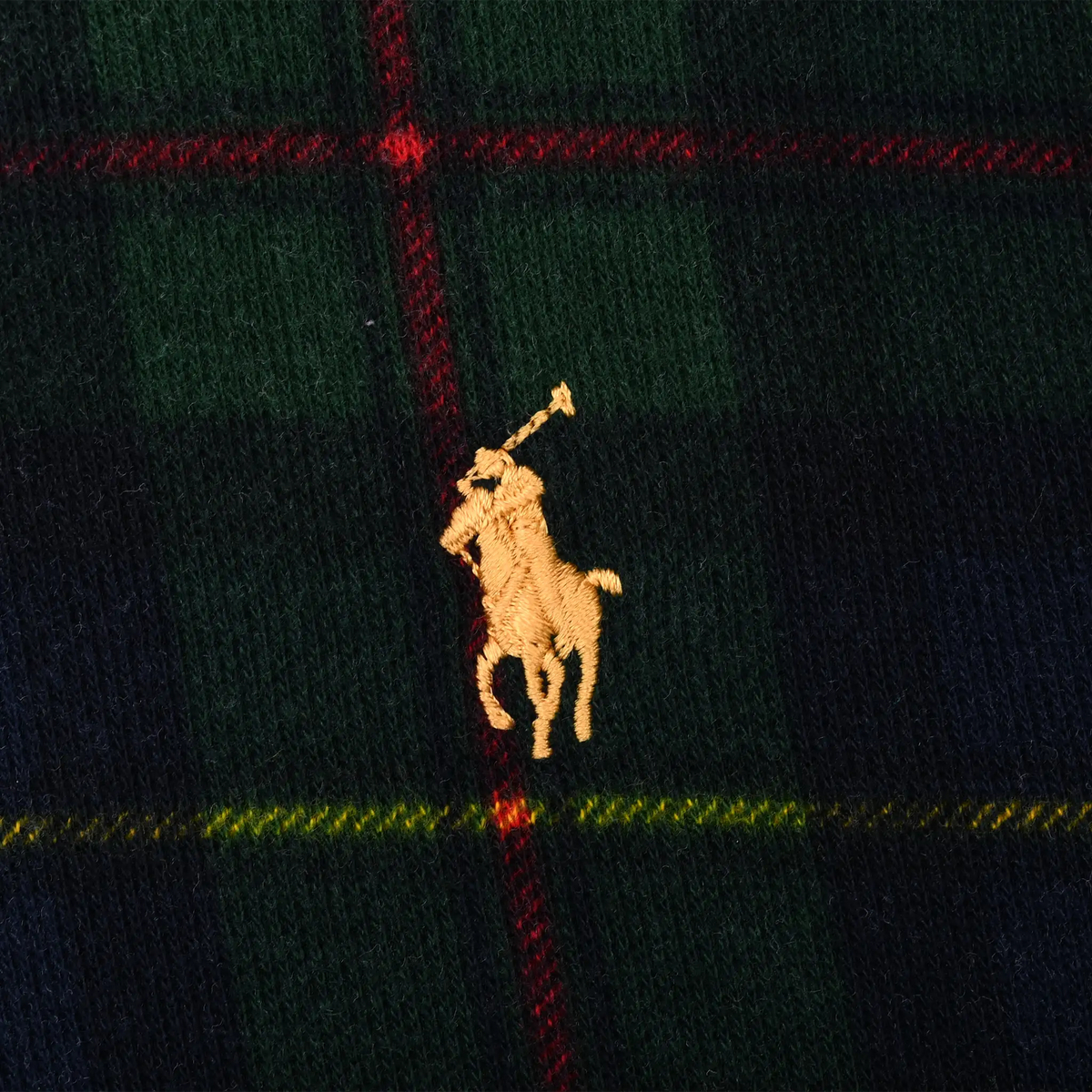 Close-up of gold Polo pony embroidery on dark green and navy plaid fabric