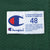Close-up of Champion size 48 jock tag and care instructions on green mesh jersey