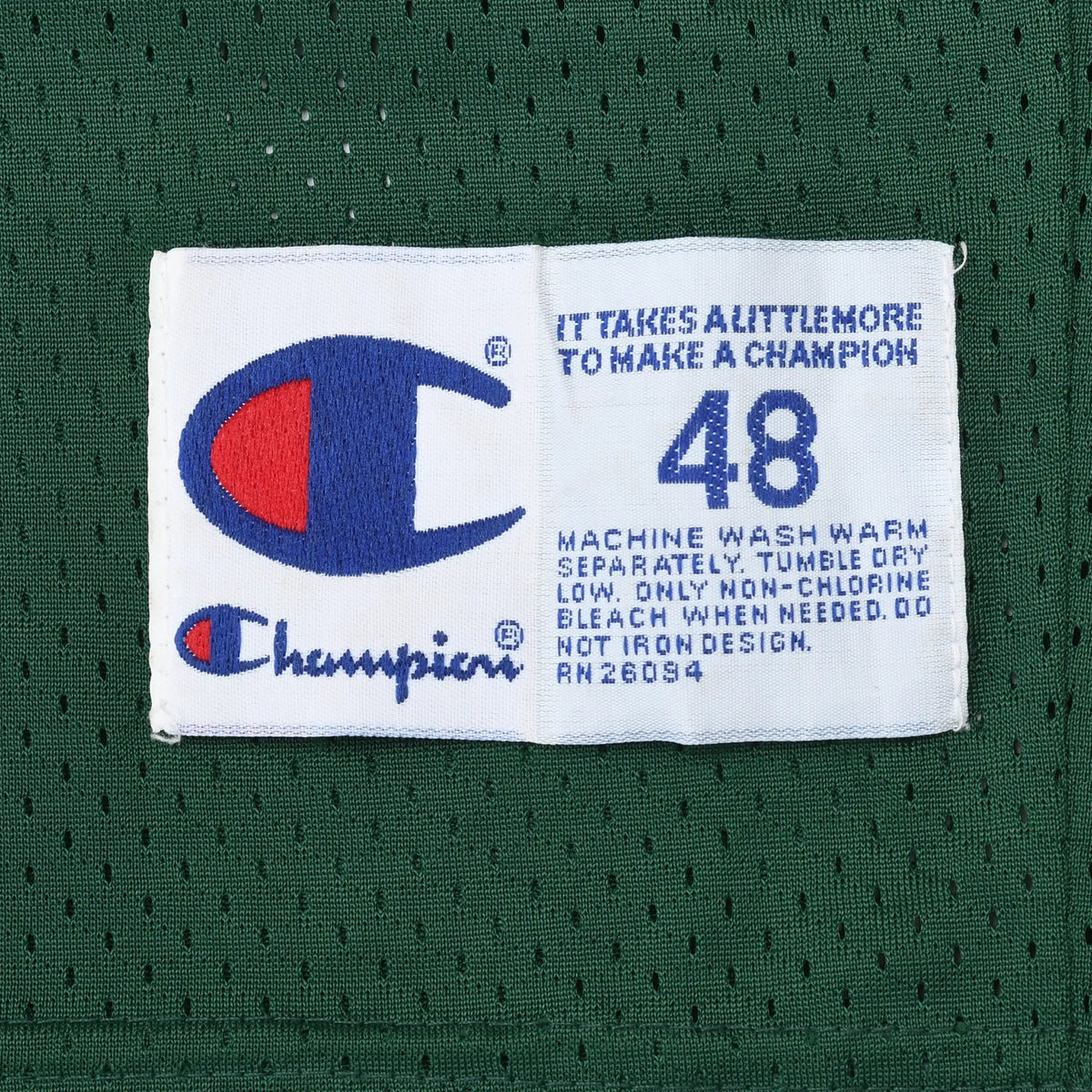 Close-up of Champion size 48 jock tag and care instructions on green mesh jersey
