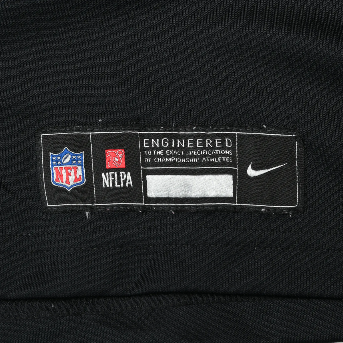 Close-up of NFL, NFLPA and Nike engineered hem label on black jersey fabric