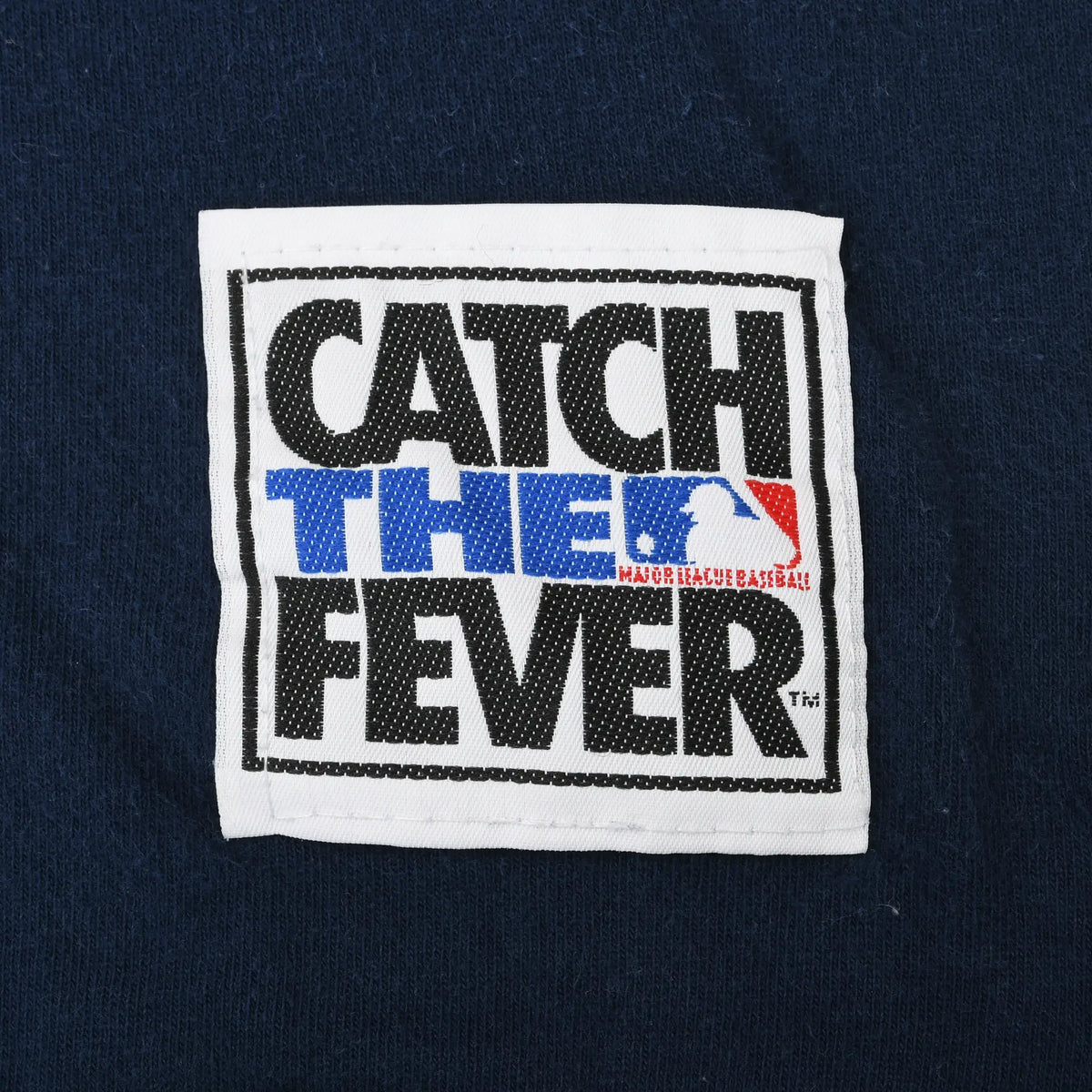 Catch the Fever MLB patch on the lower front of the navy T-shirt
