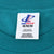 Close-up of Logo Athletic M neck label on teal T-shirt