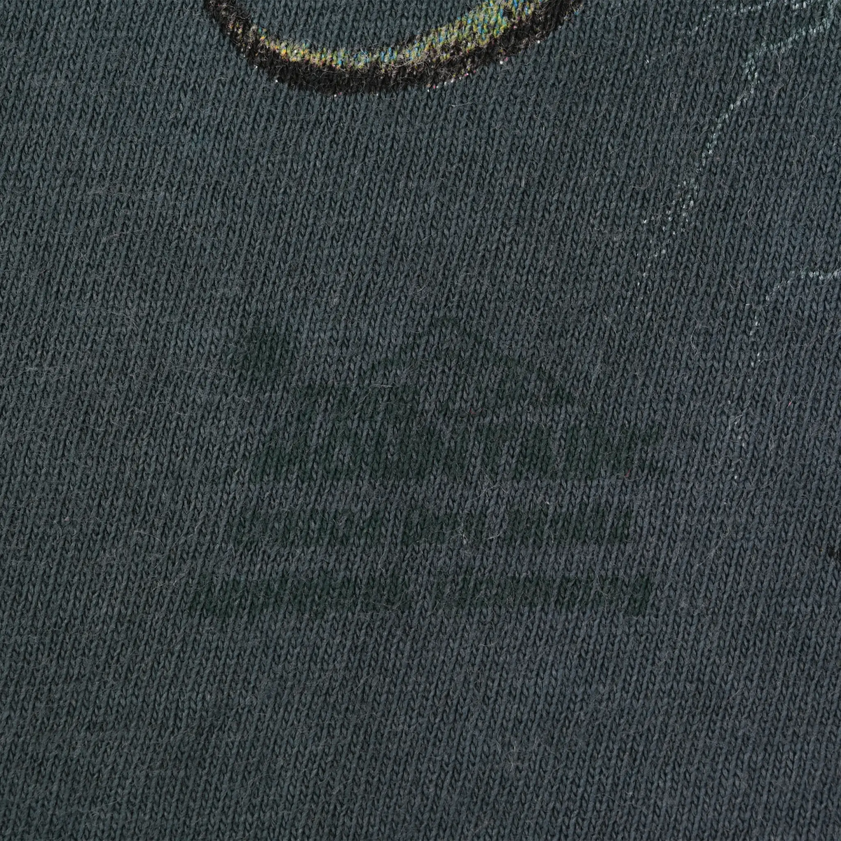 Close-up of blue-gray fabric with faint marks near the printed graphic