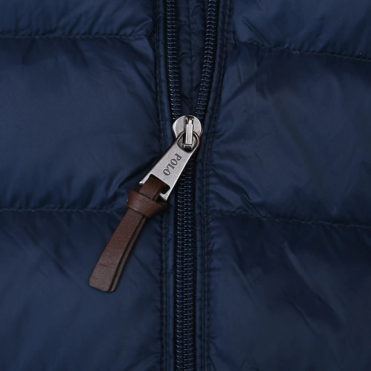 Close-up of Polo-engraved zipper pull with brown tab on navy puffer jacket