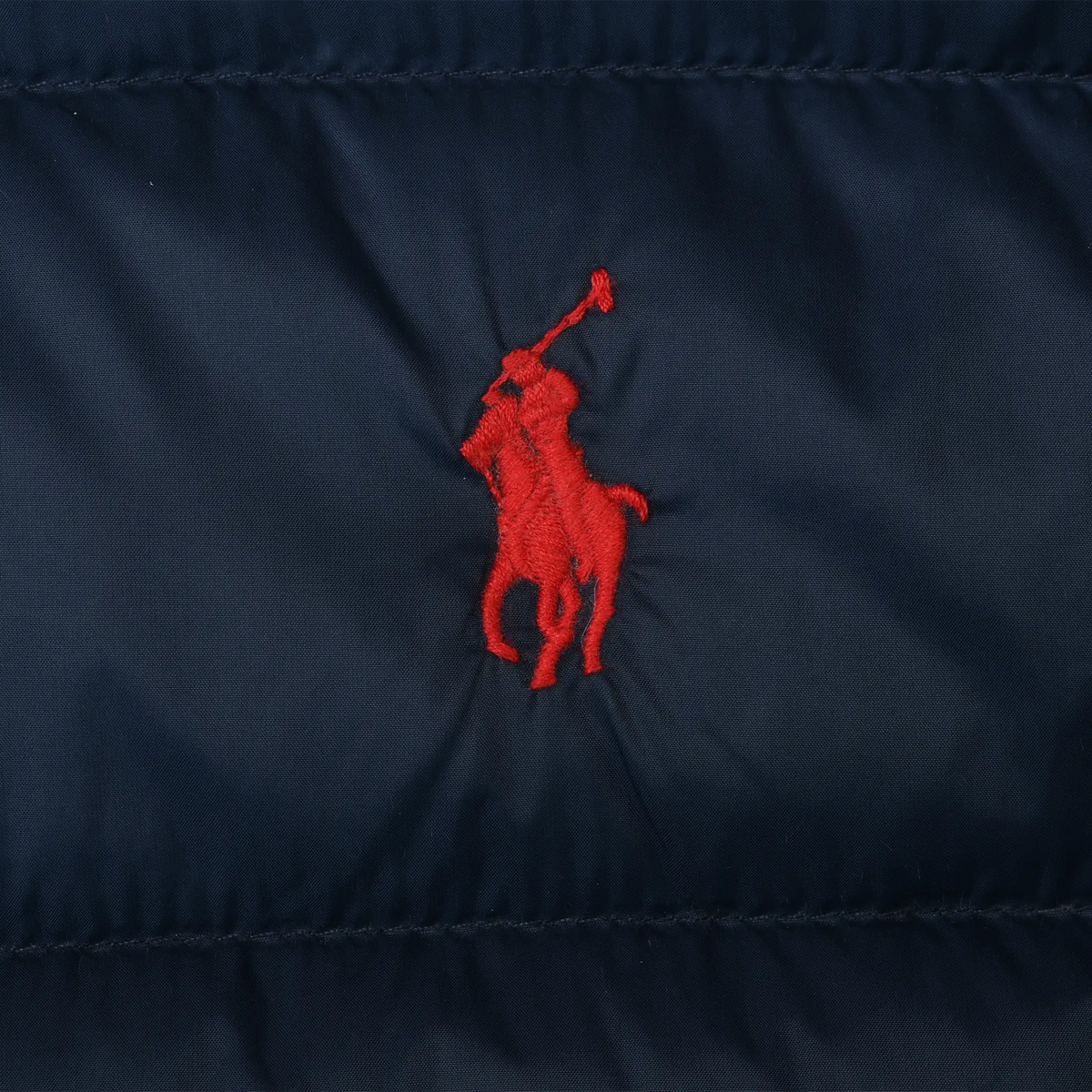 Close-up of red Polo pony embroidery on navy quilted jacket