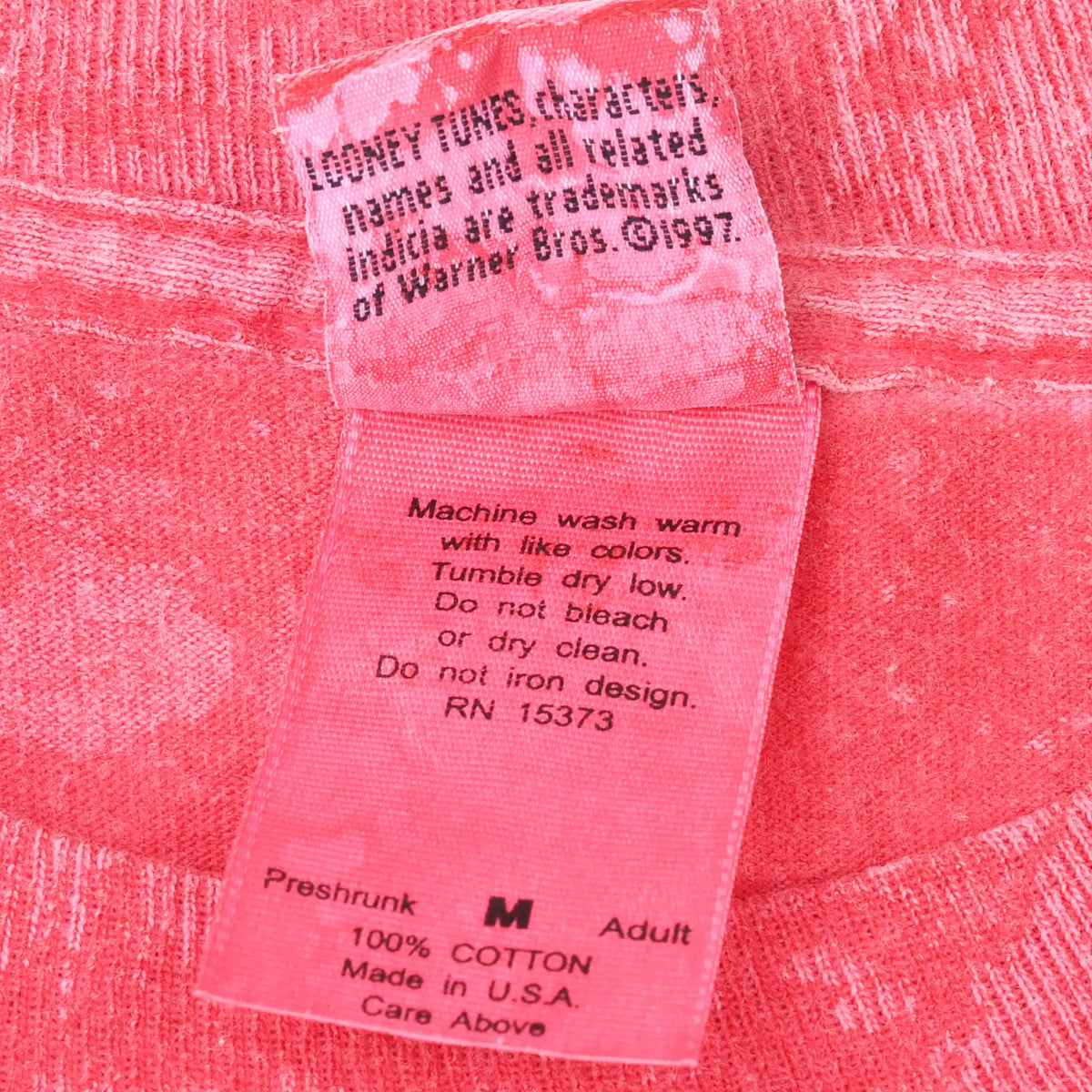 Close-up of T-shirt care label with washing instructions and Warner Bros. copyright 1997