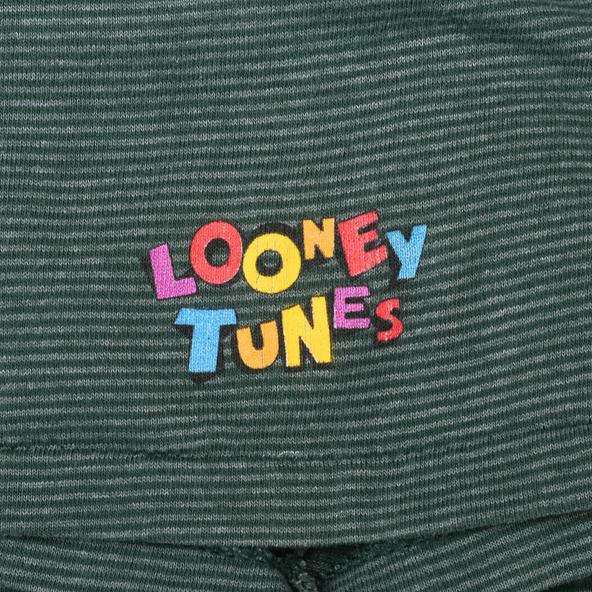 Close-up of multicolor Looney Tunes sleeve print on green striped fabric