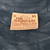 Close-up of The Mountain neck label marked XL, 100% cotton, dyed and printed in USA