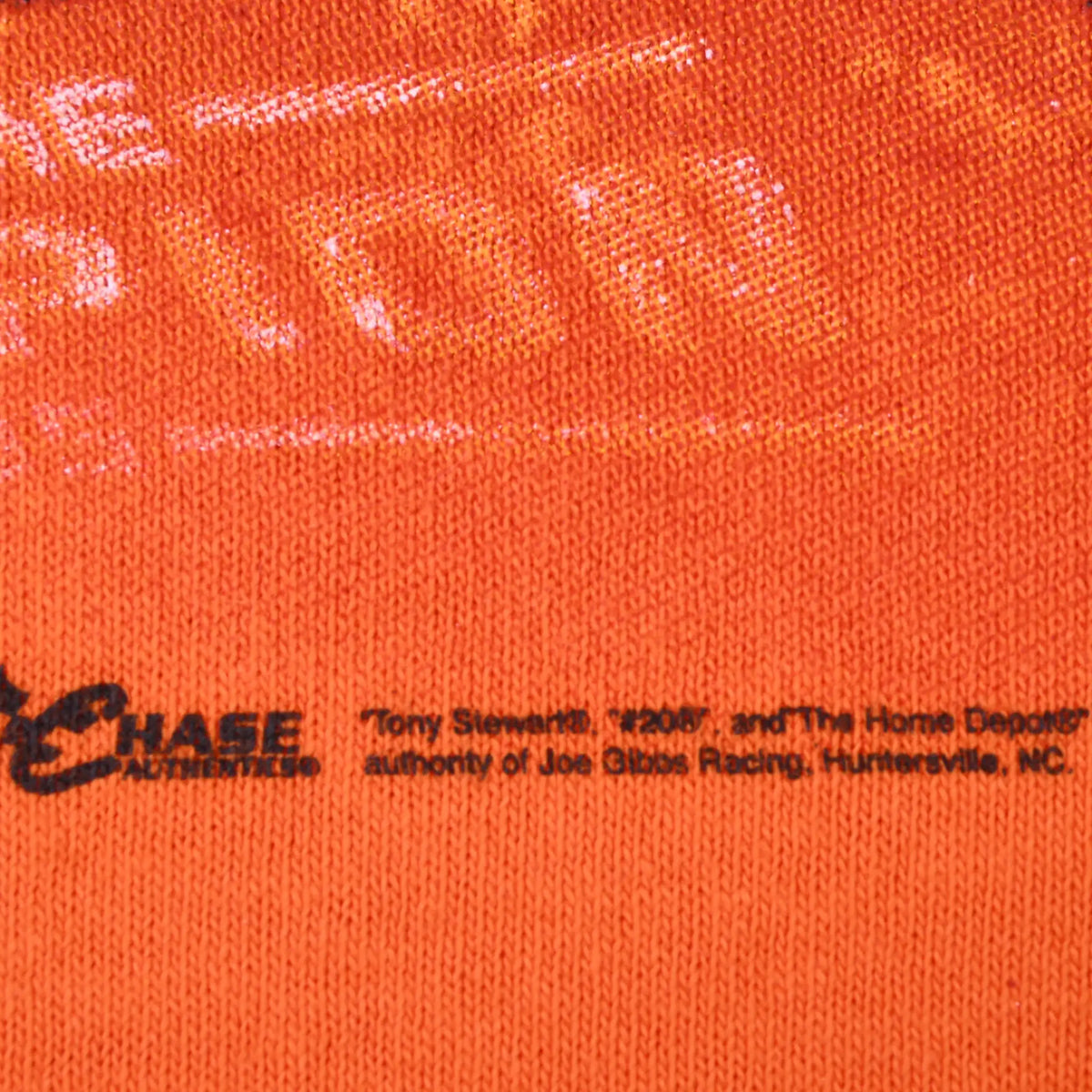 Close-up of Chase Authentics and Tony Stewart copyright print on orange fabric