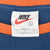 Nike neck tag marked size L and Made in USA inside blue shirt with orange collar
