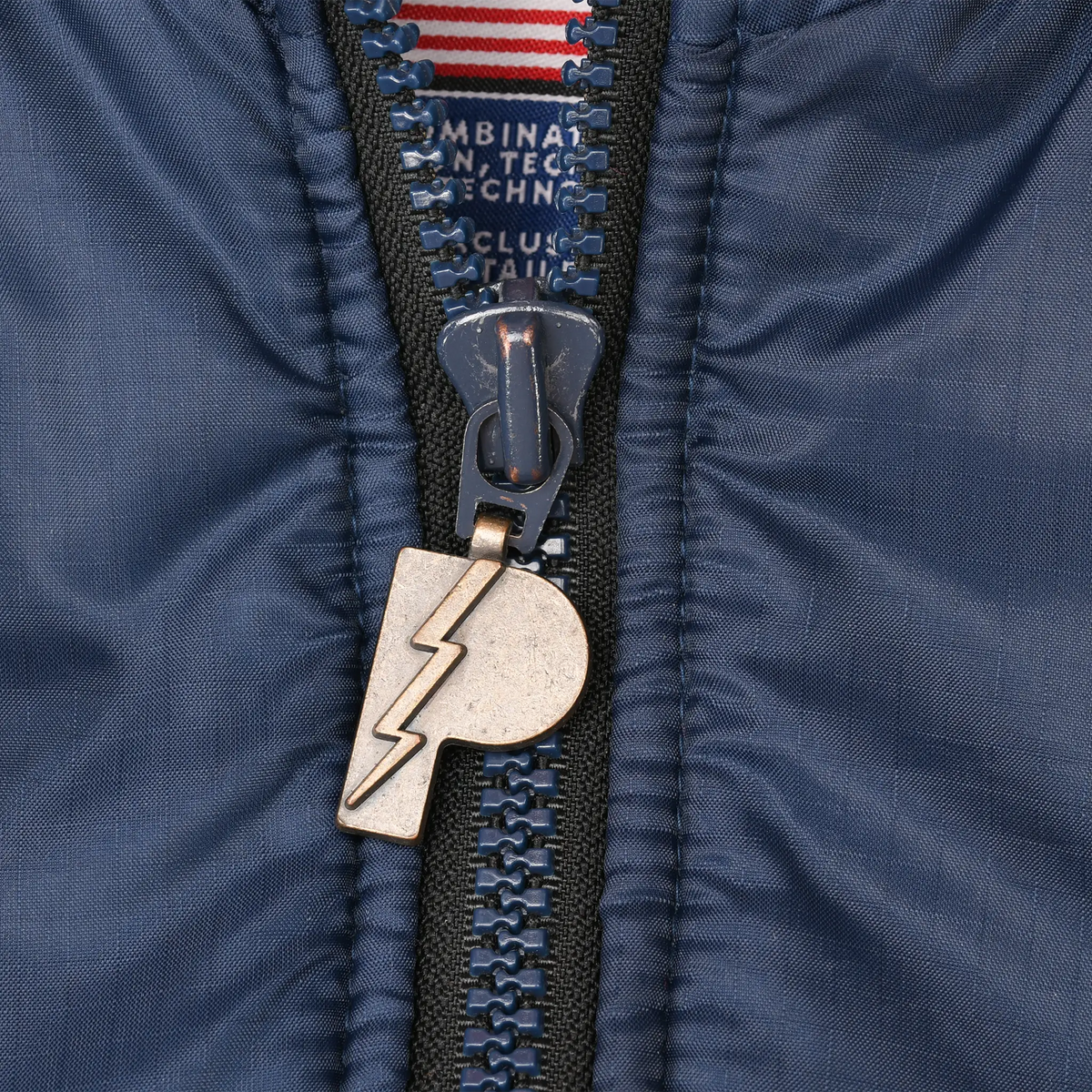 Close-up of metallic Pro Player logo zipper pull on navy jacket fabric